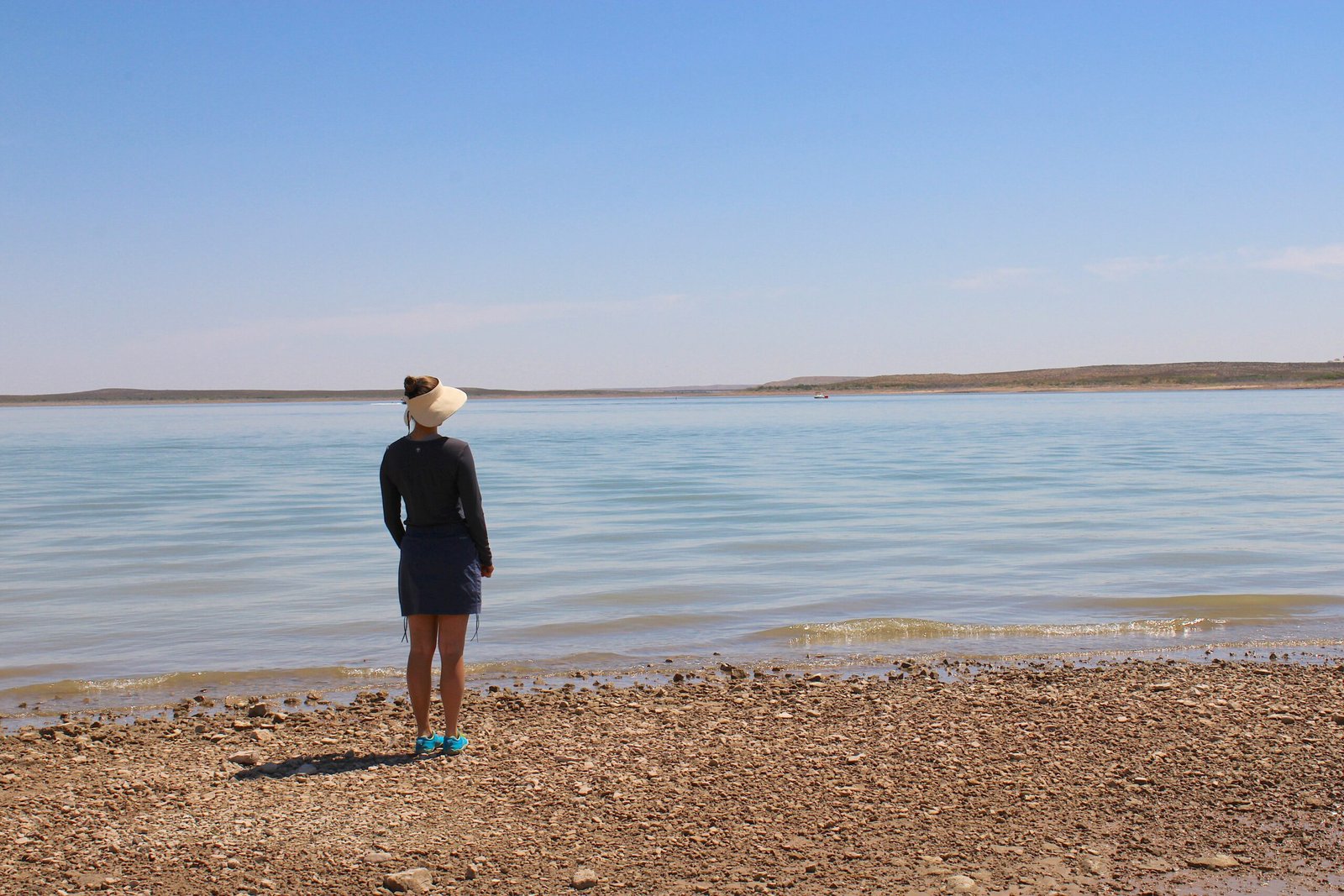 Woman standing near the scenic shoreline and campground at Brantley Lake State Park with desert hills in the background.