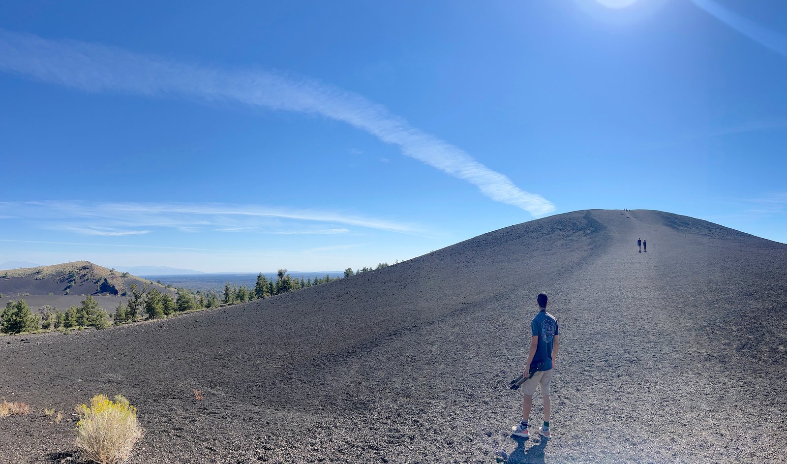 Hiker climbing the black cinder trail on Inferno Cone at Craters of the Moon National Monument in Idaho