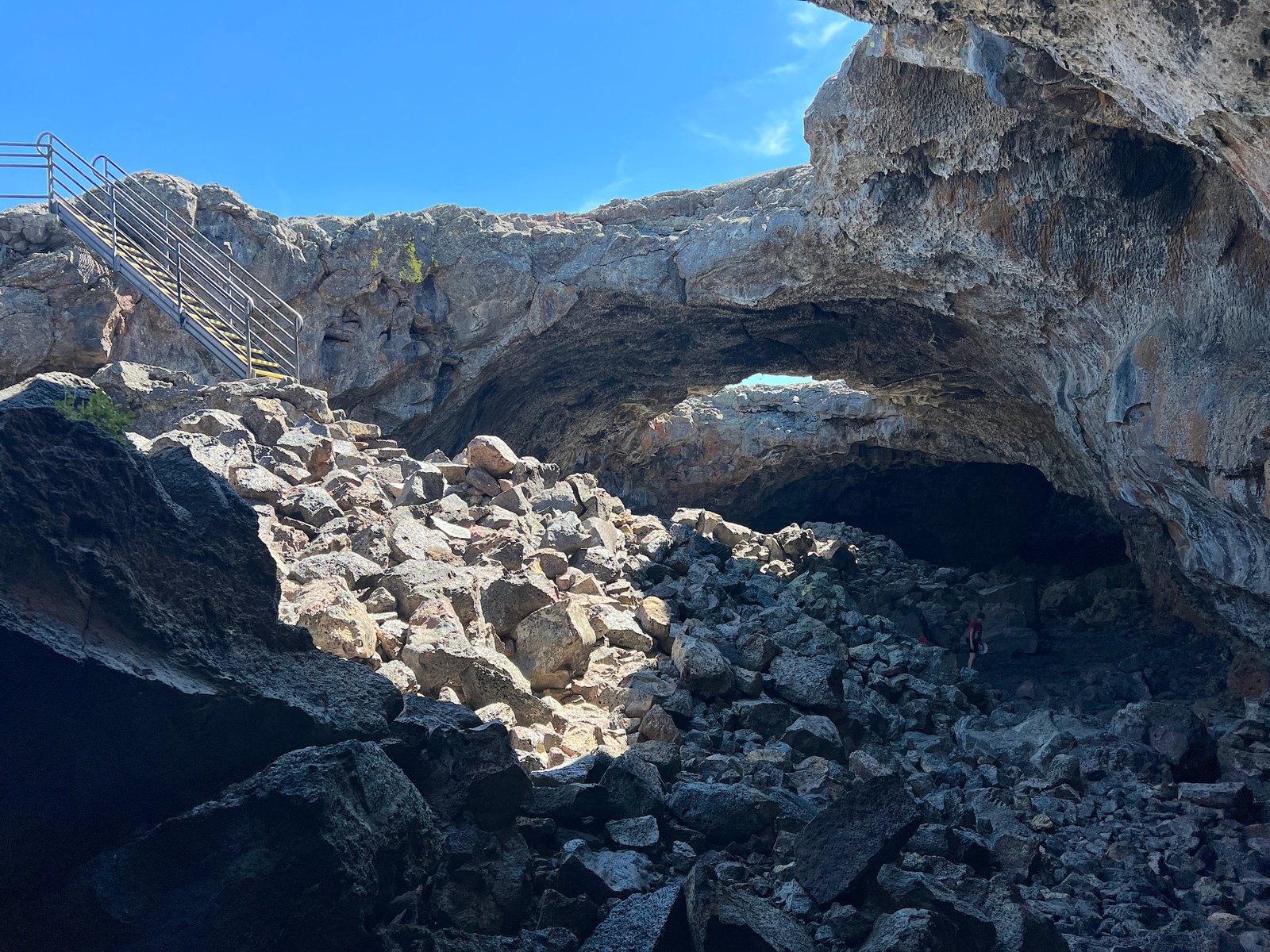 Metal staircase leading down into the massive stone opening of Indian Tunnel cave at Craters of the Moon