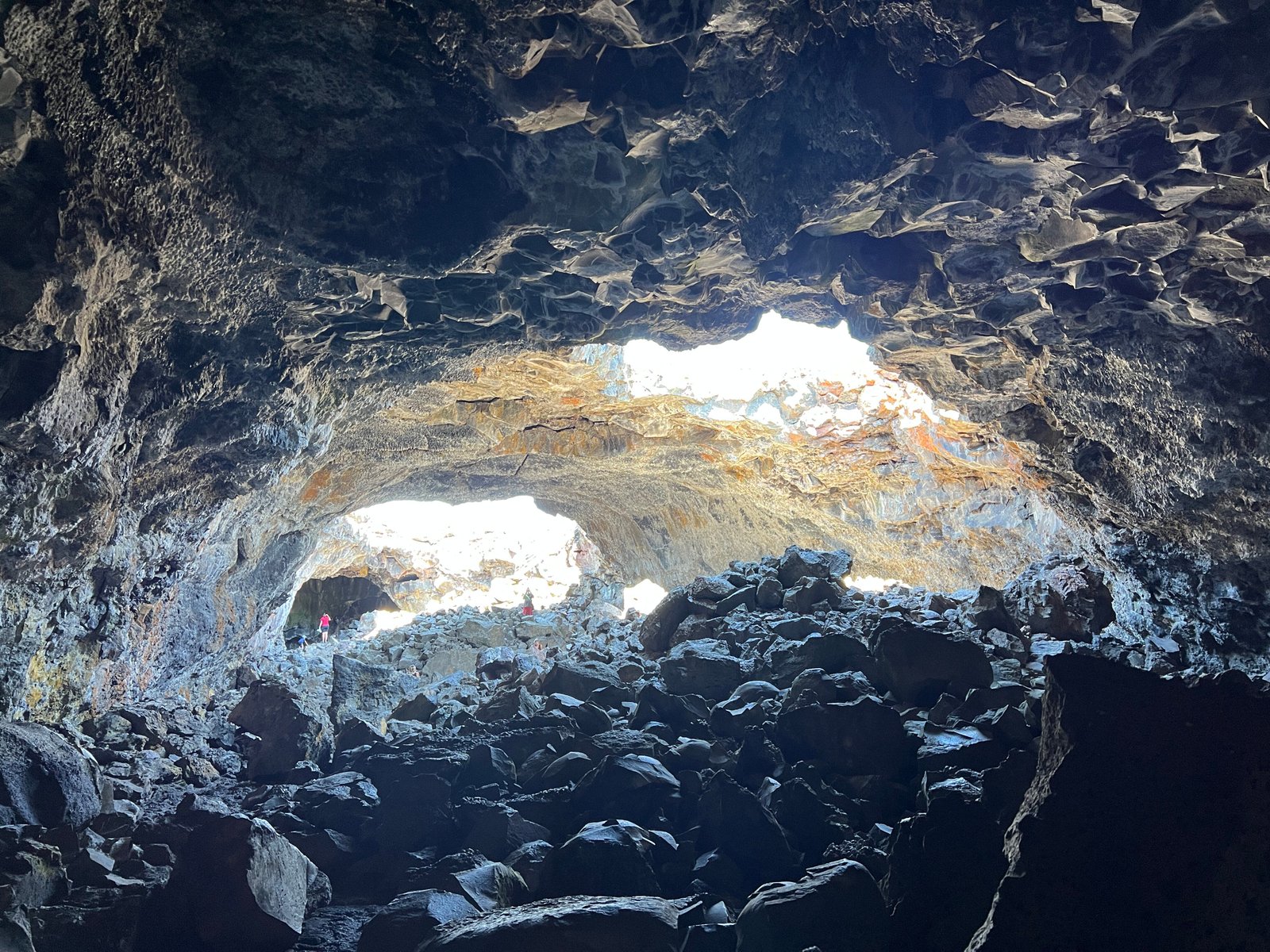 Sunlight streaming through two large ceiling openings on the rocky floor inside Indian Tunnel cave at Craters of the Moon