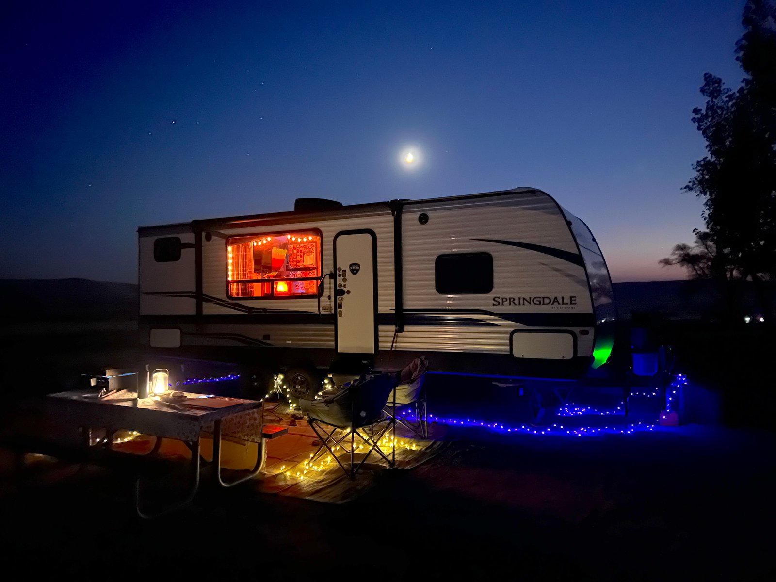A travel trailer and truck parked at the campground under a dark starry sky at Bruneau Dunes State Park in Idaho.