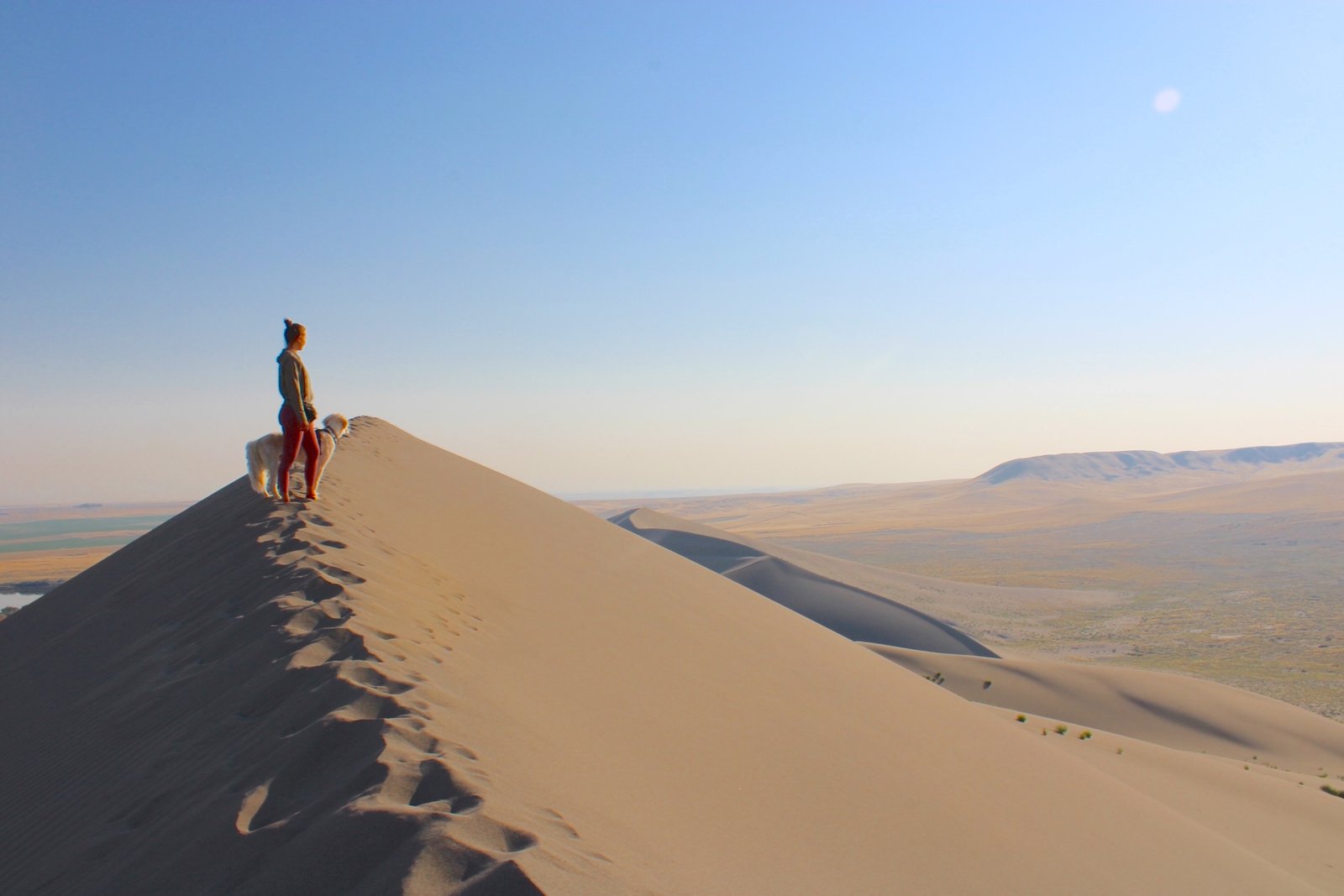 Hiker standing on the ridge of the massive sand dunes overlooking the desert basin at Bruneau Dunes State Park in Idaho.