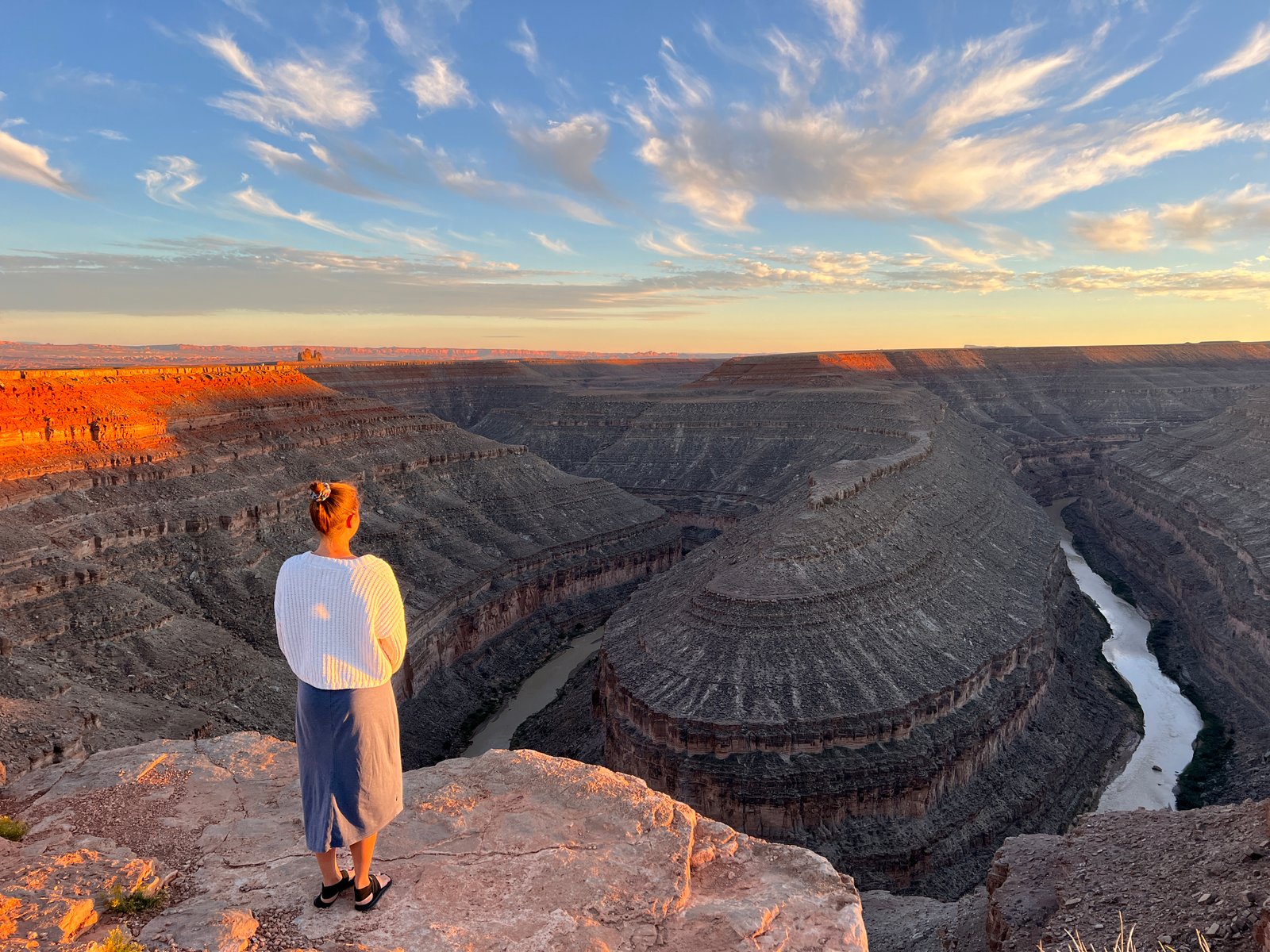 person standing on cliff edge with canyon and river below