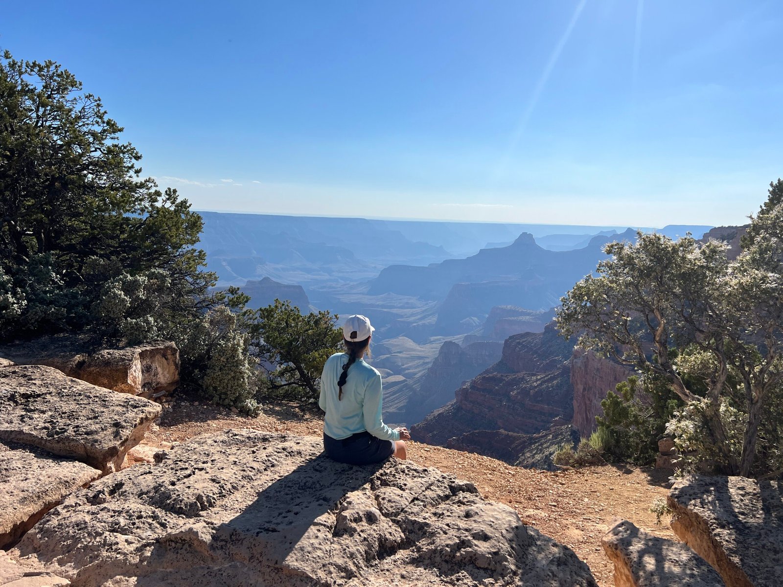 person sitting on rock with Grand Canyon in the background