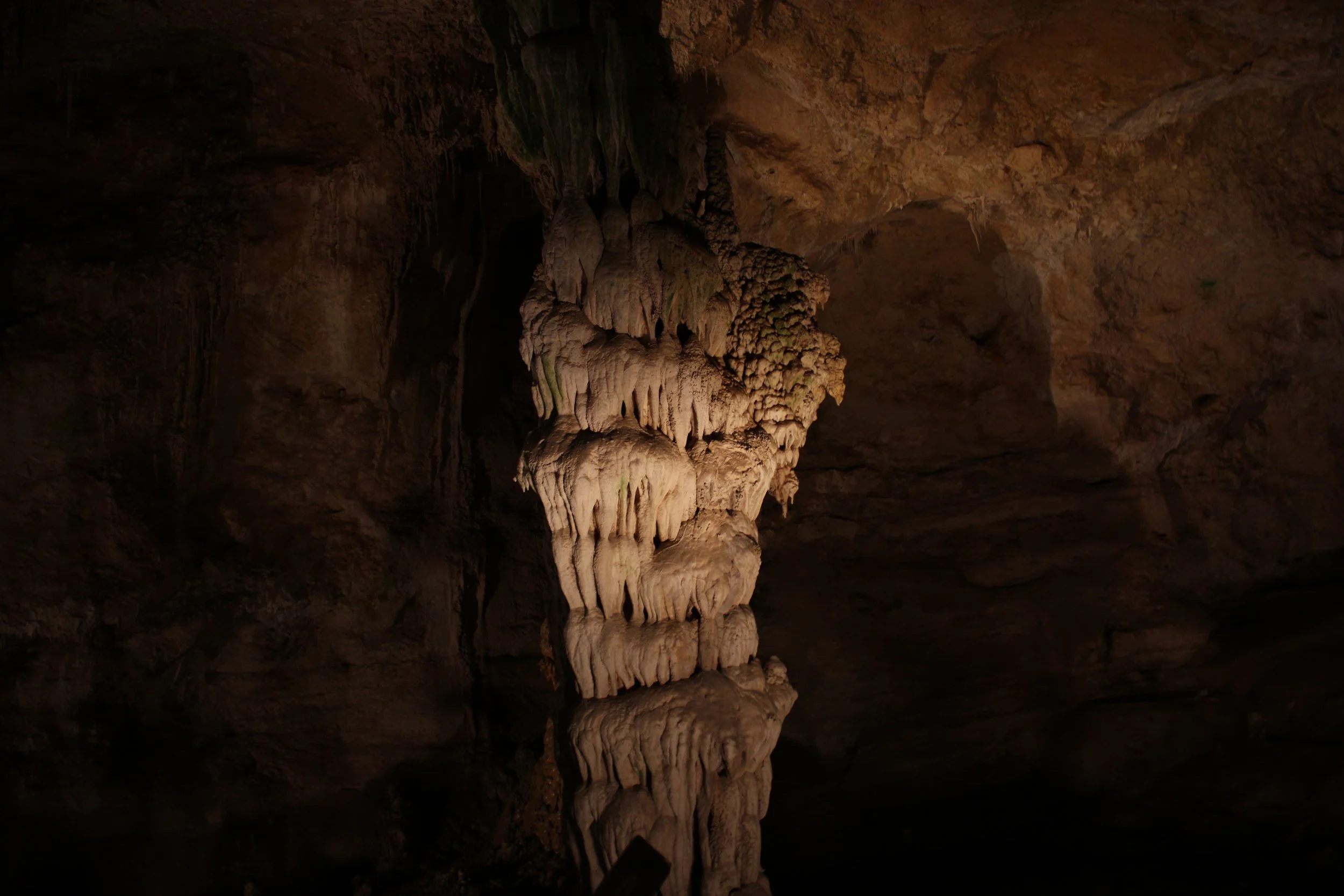 Close-up view of delicate, dramatic stalactites and cave formations brilliantly illuminated by warm track lighting inside Carlsbad Caverns.