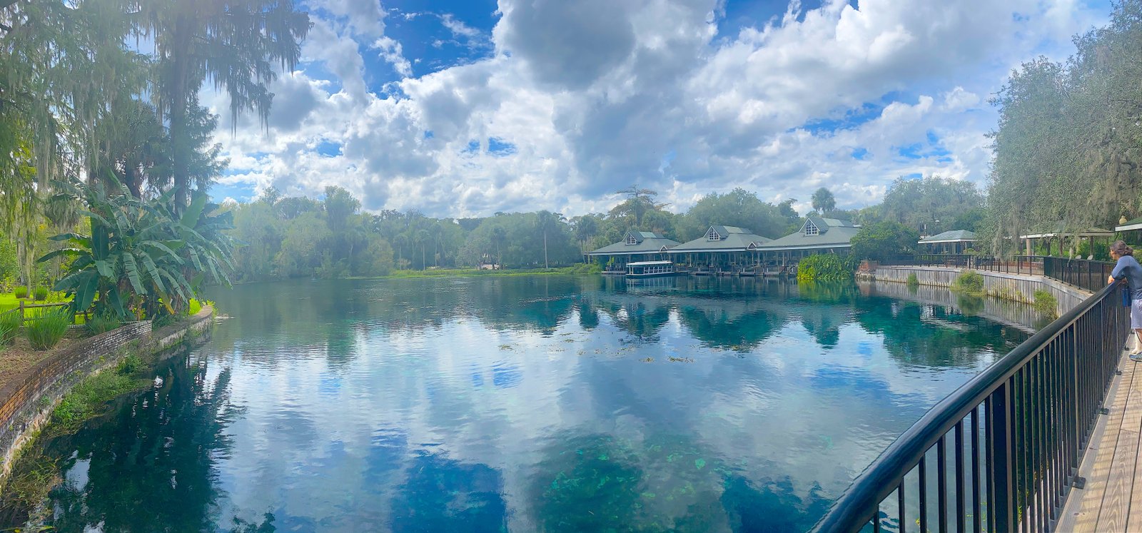Panoramic view of the crystal-clear spring head and historic structures reflecting on the water at Silver Springs State Park.