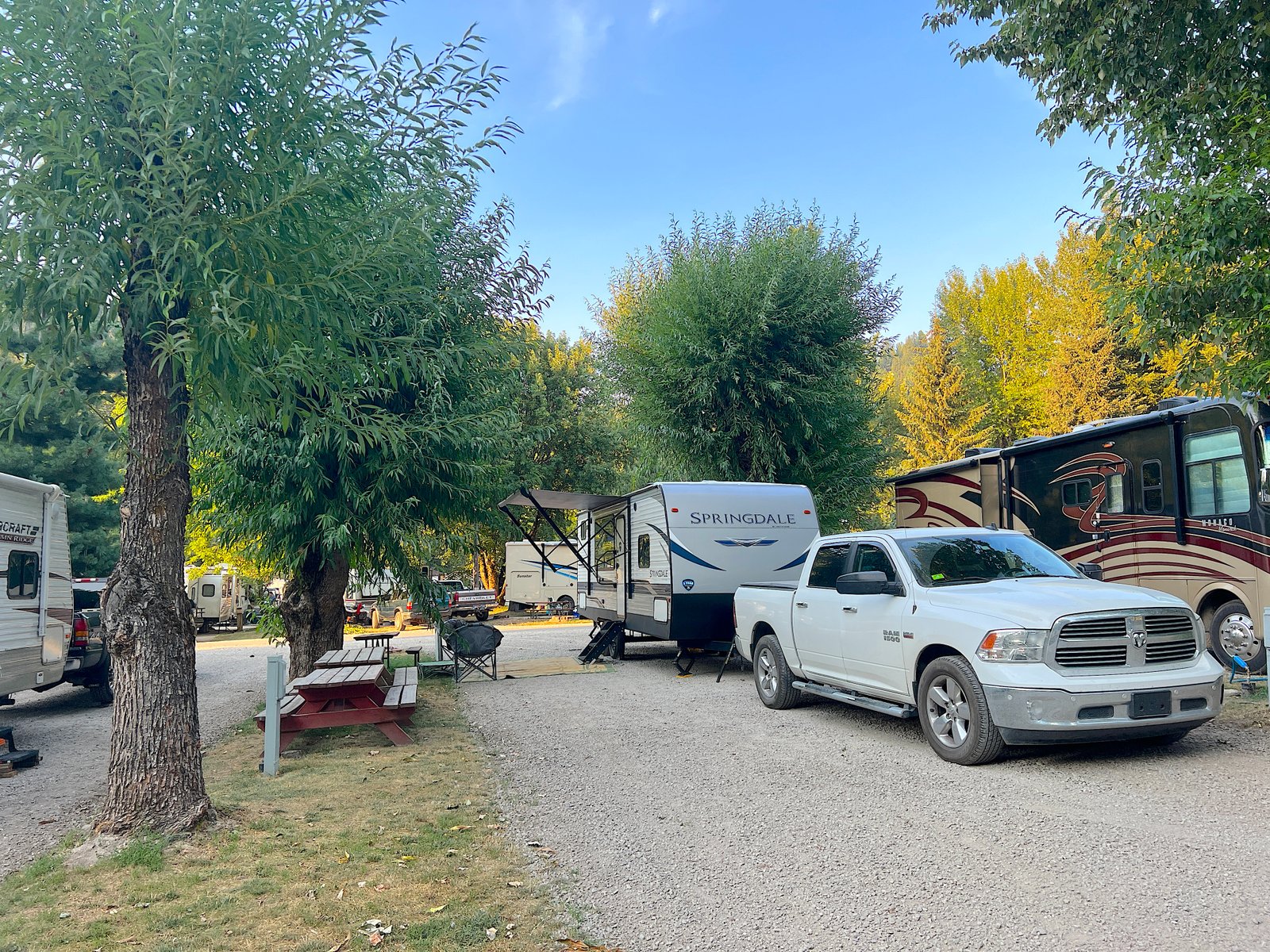 Travel trailer and pickup truck parked at a campsites surrounded by trees at Blue Anchor RV Park near Wallace, Idaho.