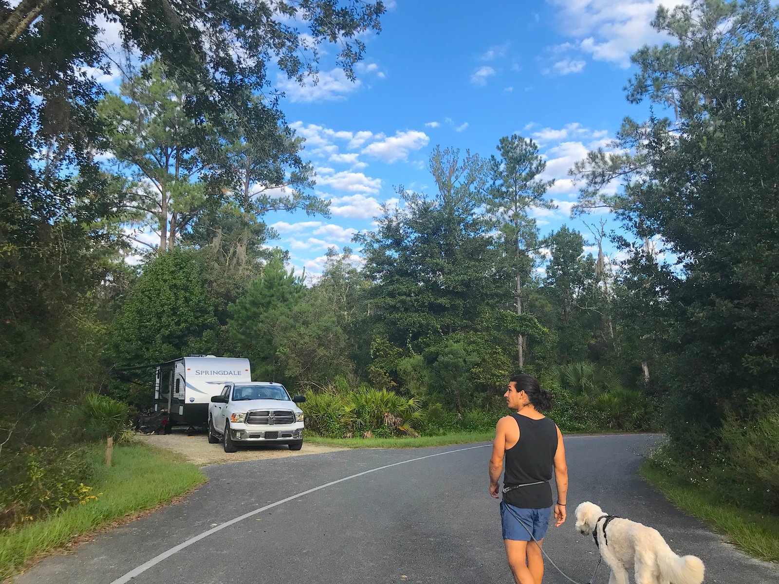 Man and golden retriever dog walking toward a wooded campsite at the Rainbow Springs State Park campground in Florida.