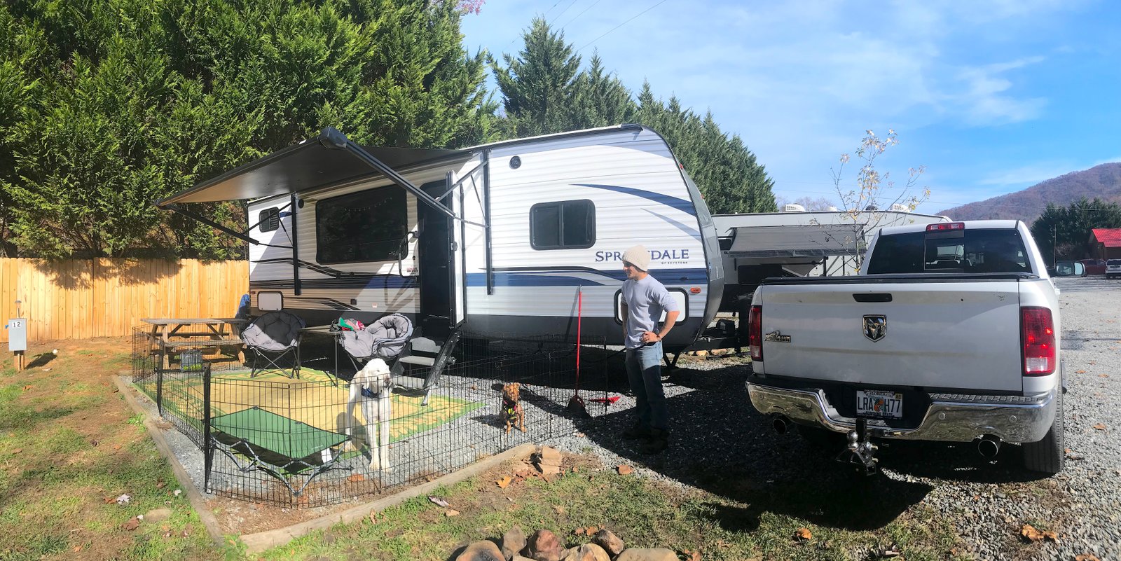 Two dogs relaxing in an outdoor gated patio area next to a parked RV at Grumpy Bear RV Park in the Smoky Mountains.