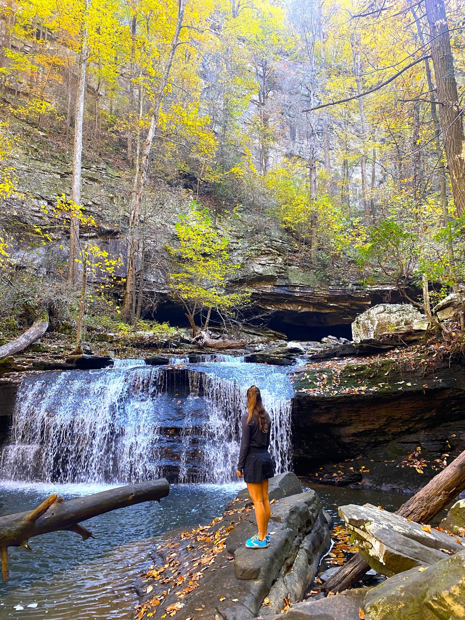 woman standing on rock looking at waterfall
