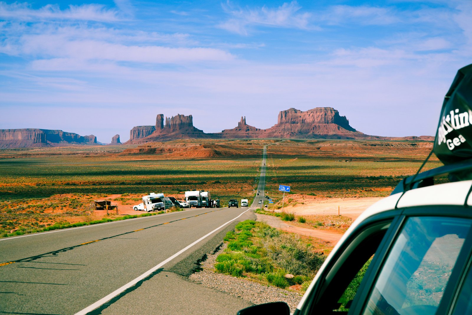 cars parked on side of the road with red rocks in the distance