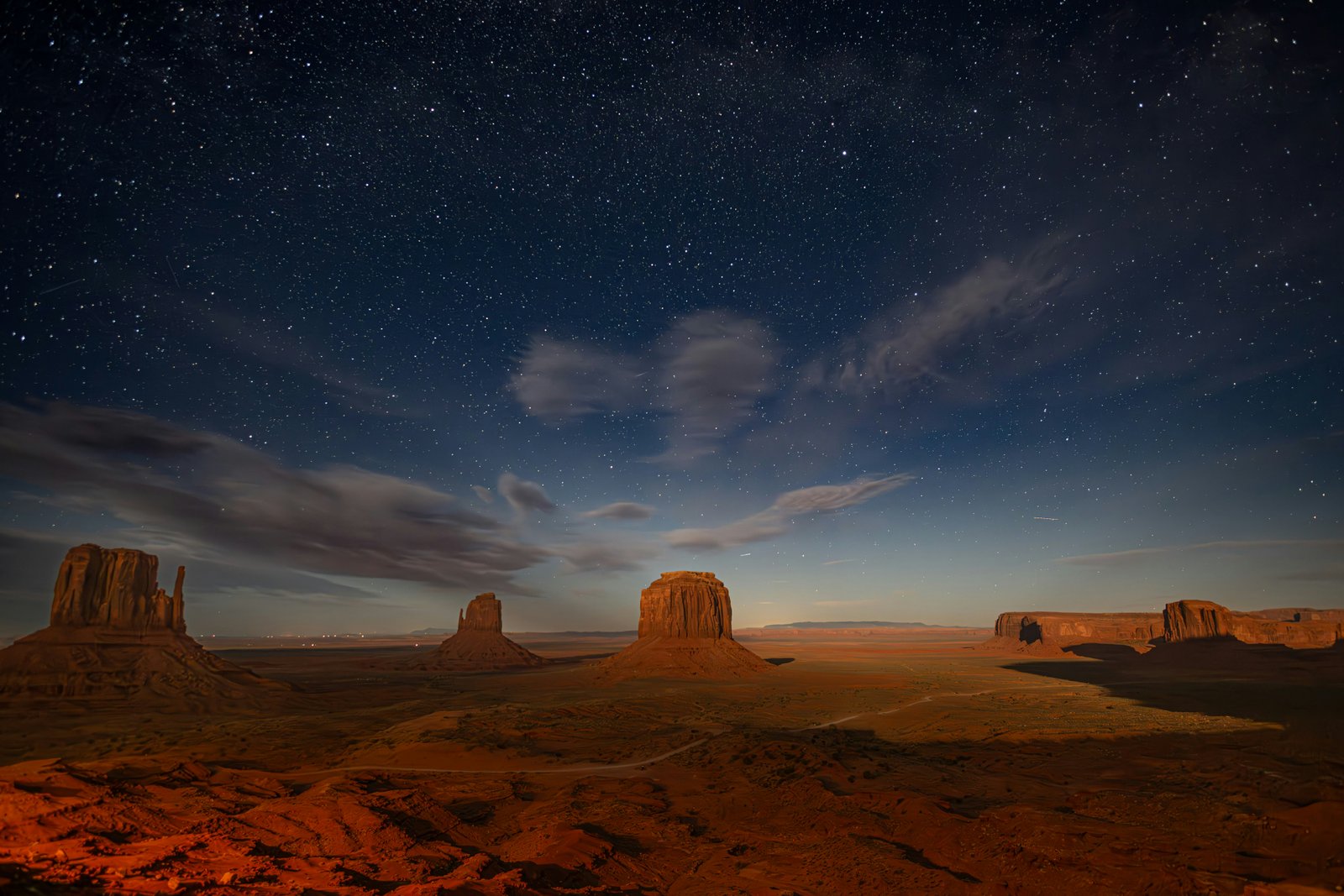 red rock valley below a starry night sky