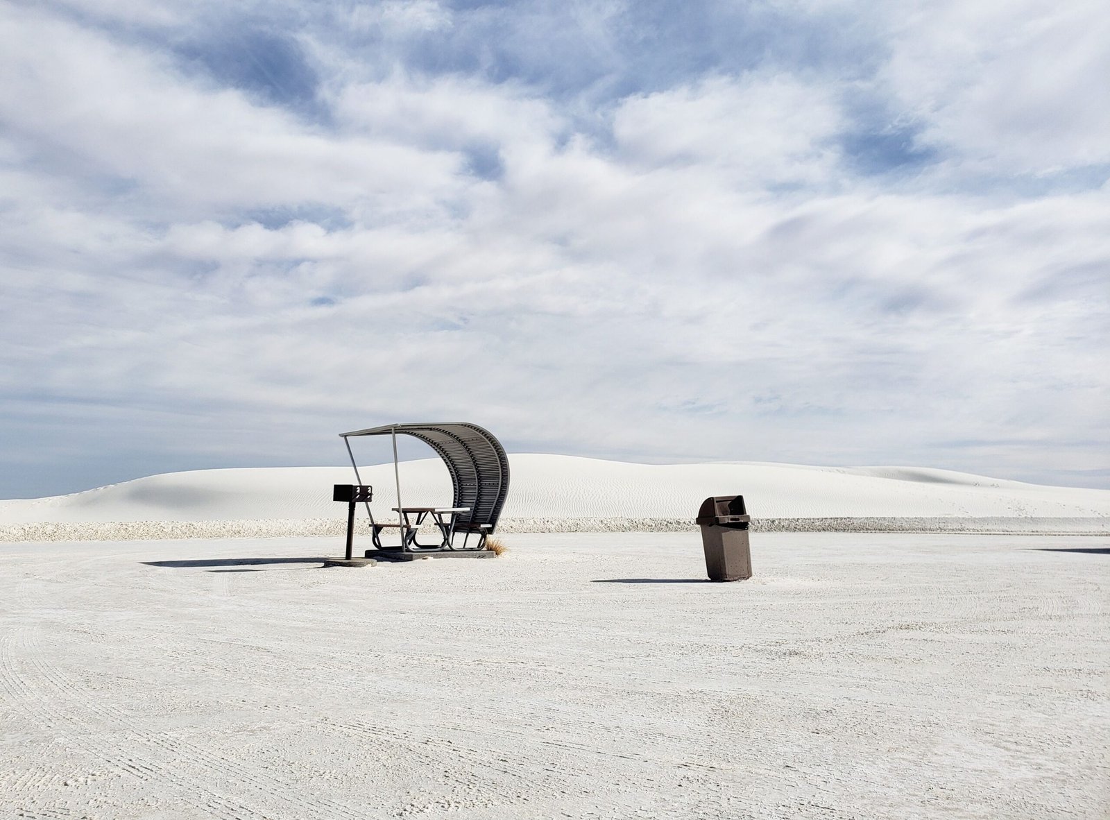 silver metal shaded picnic tables surrounded by rolling white gypsum dunes along Dunes Drive at White Sands National Park.