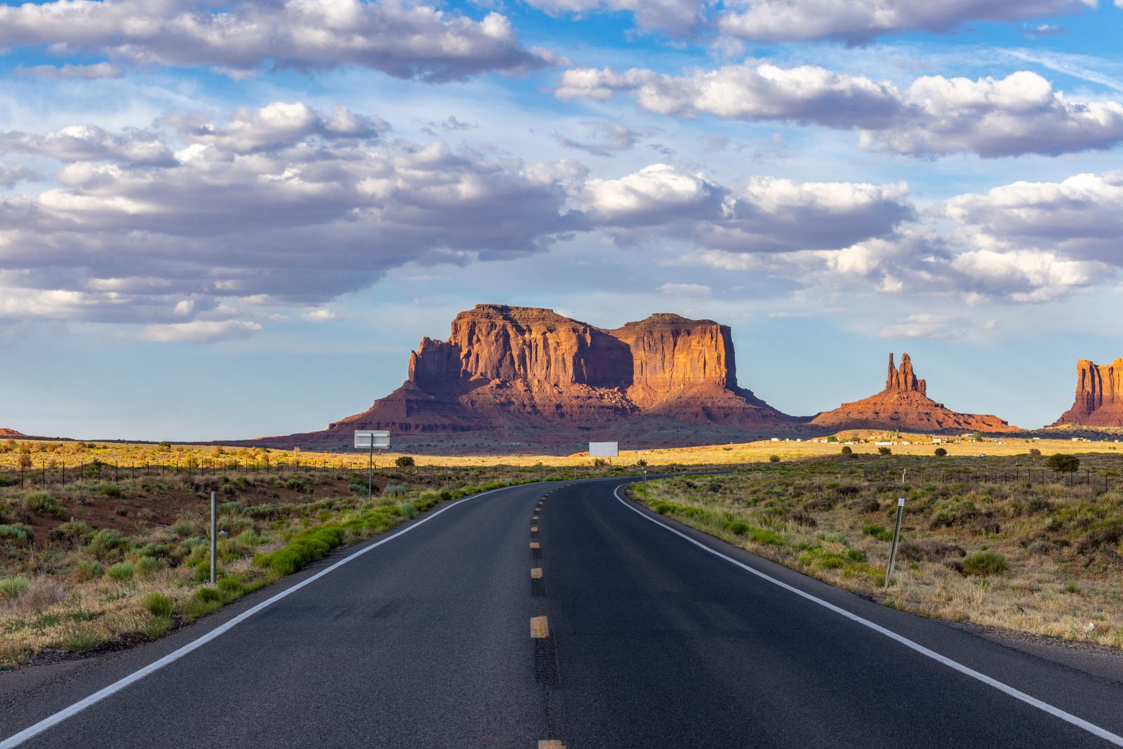road with red rock in the distance and sunset glow