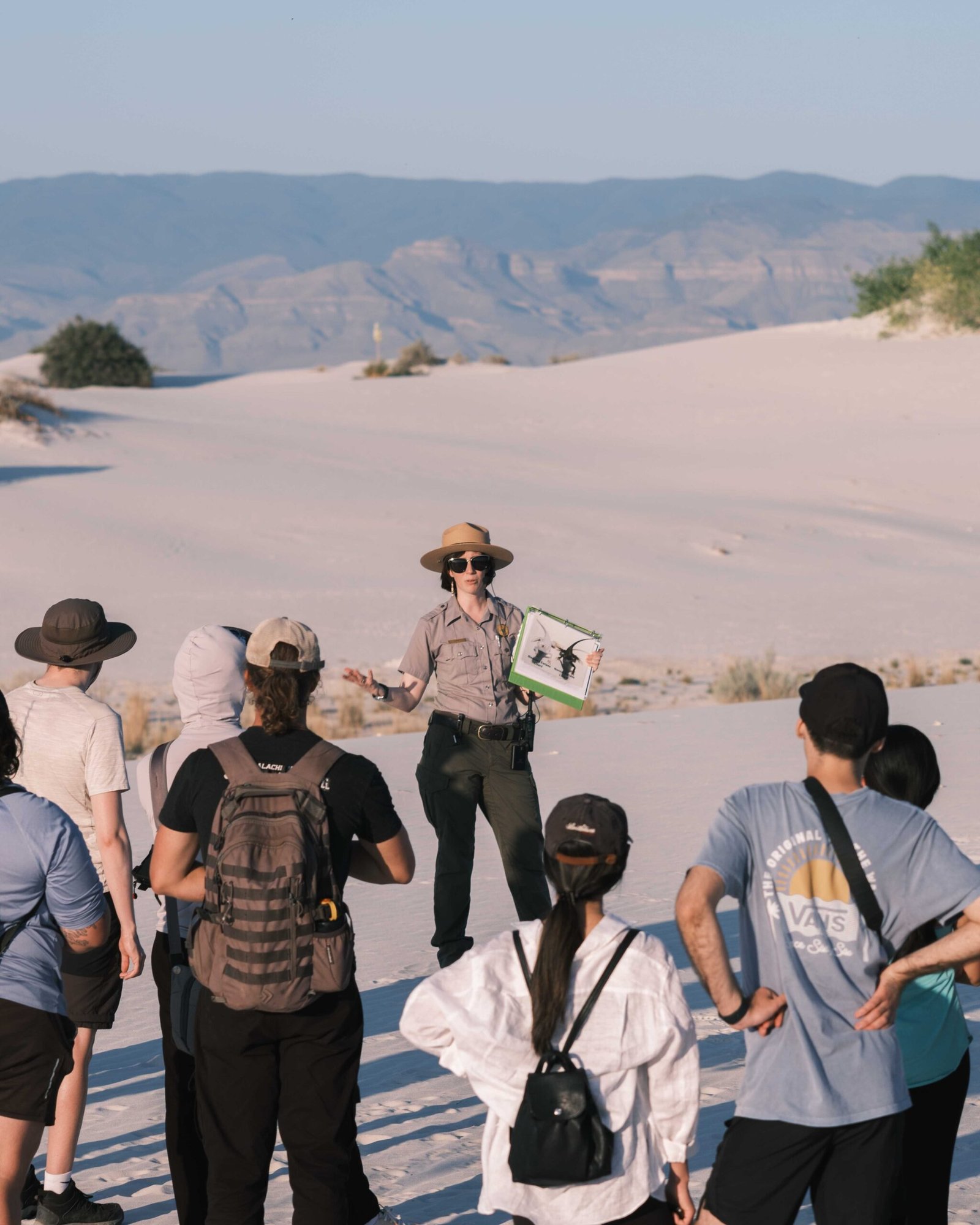 Visitors gathered on the white gypsum dunes listening to a National Park Service ranger during an educational ranger-led program at White Sands National Park.