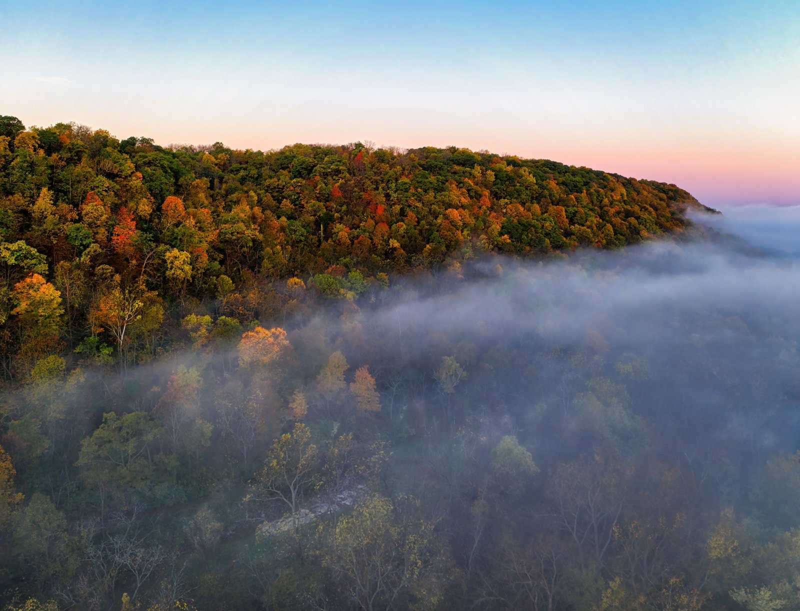 mist rolling over mountain with fall colors and colorful morning glow