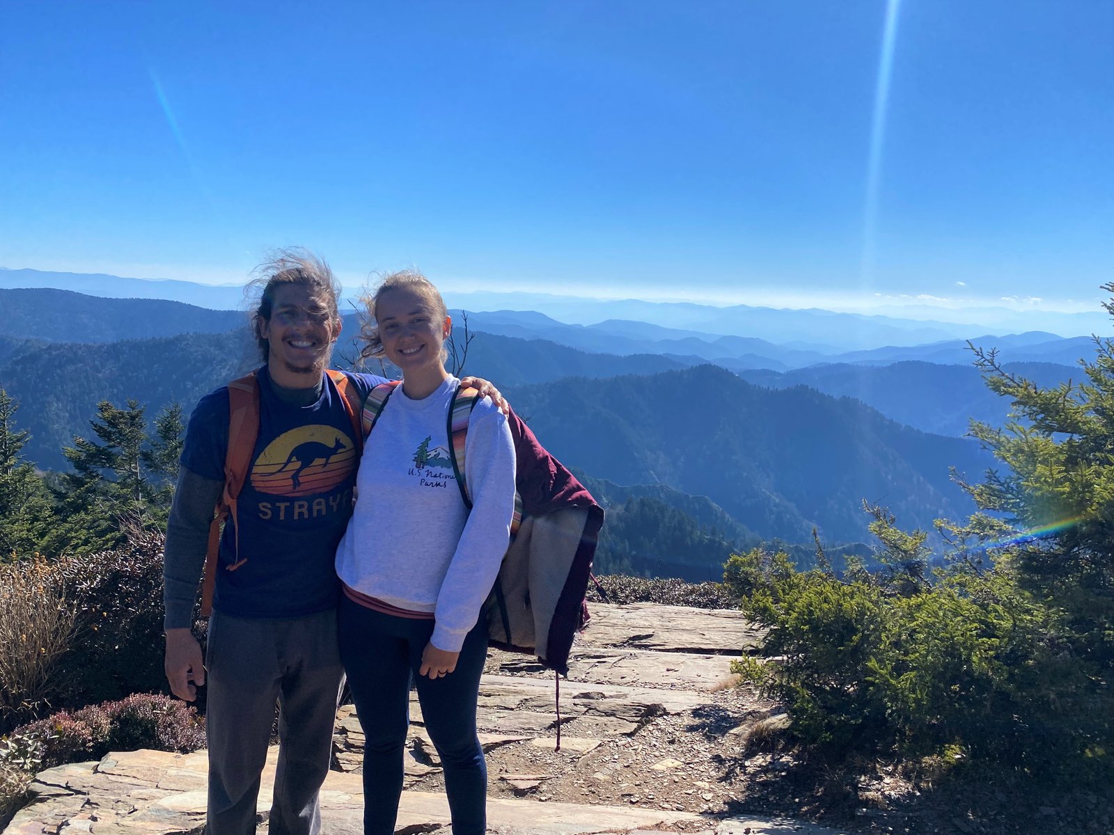 A smiling couple posing together with sweeping panoramic mountain views at Myrtle Point near the summit of Mount LeConte in the Great Smoky Mountains.