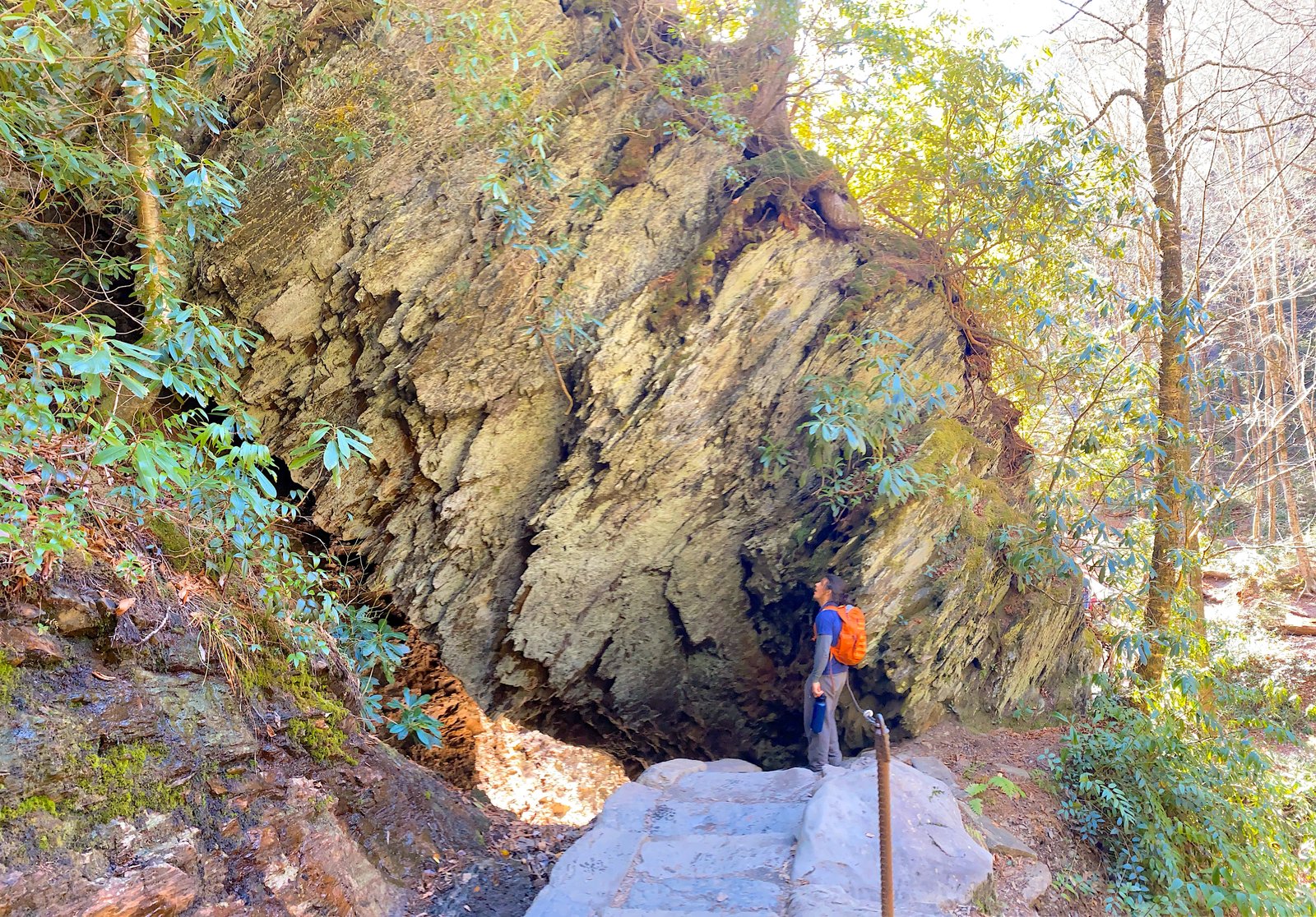 Hiker navigating the rugged rock formations and cable-assisted trail on the Alum Cave Trail to Mount LeConte in the Great Smoky Mountains.