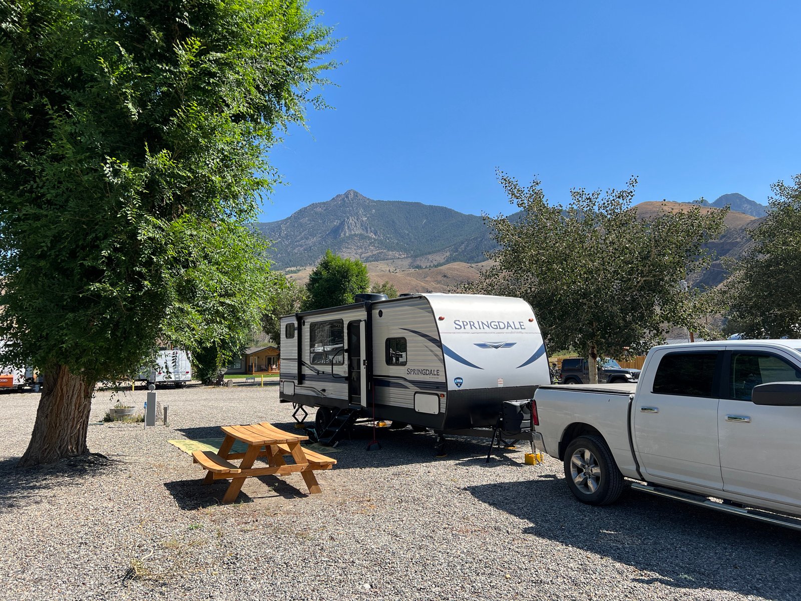 A pickup truck and travel trailer parked at a scenic campsite at Elk Bend RV Park near Goldbug Hot Springs in Idaho.