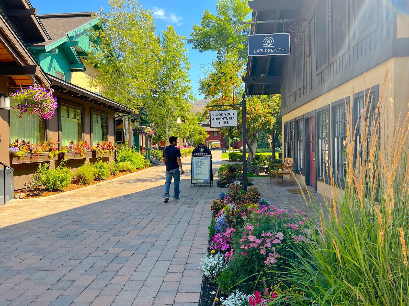 A man walking past vibrant summer flower beds on the scenic grounds of Sun Valley Resort in Idaho.