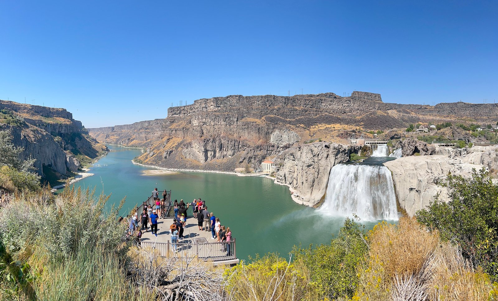 Wide angle view of the massive Shoshone Falls with visitors looking out from the lower viewing area, Idaho.