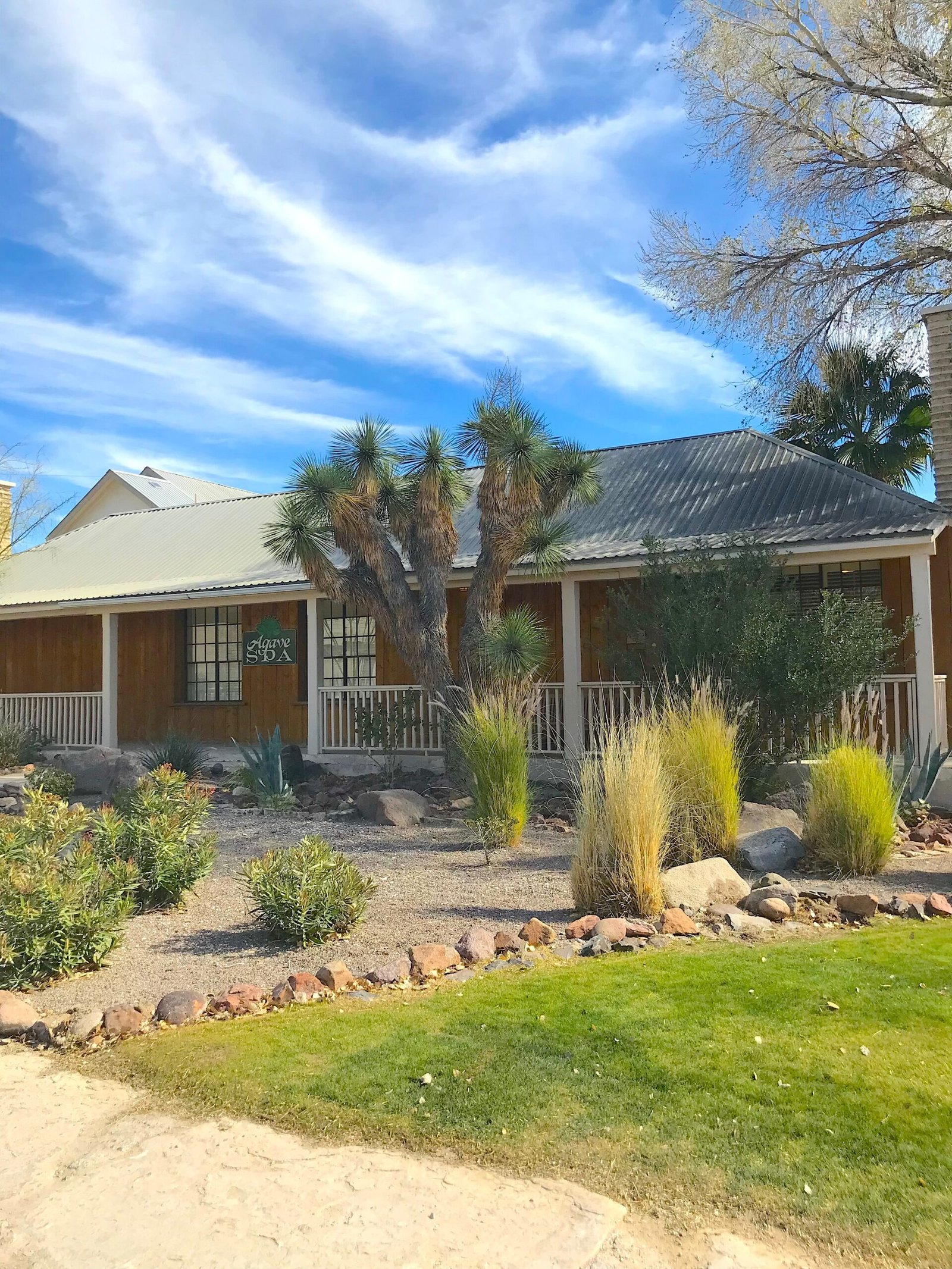Exterior view of the rustic southwestern Agave Spa building at Lajitas Golf Resort surrounded by desert landscaping.
