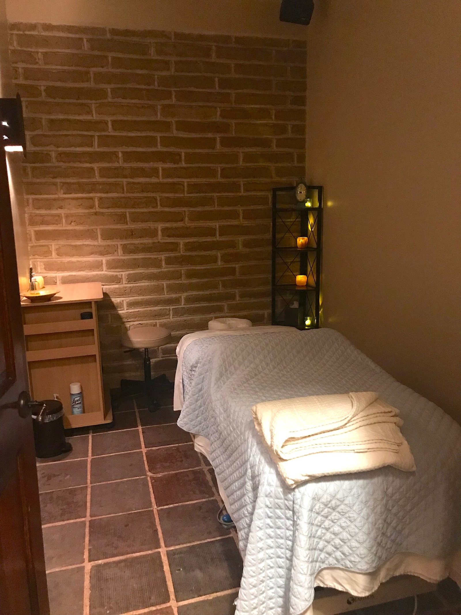 Peaceful spa treatment room at Lajitas Golf Resort featuring a massage table, warm lighting, and rustic brick walls.