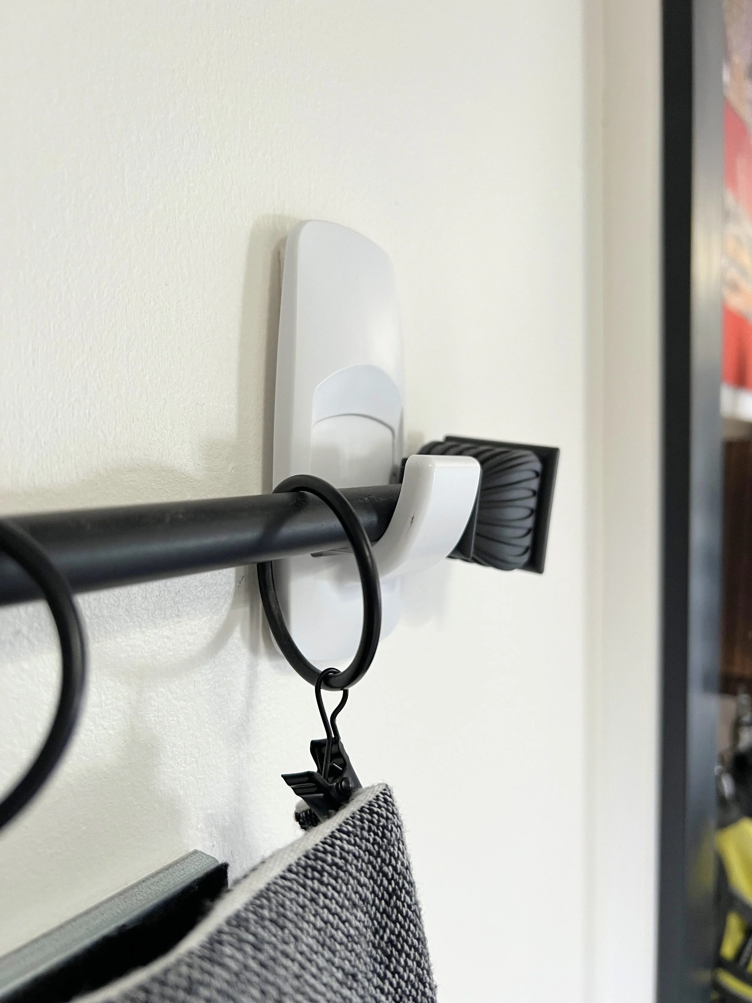 Close-up of a black curtain rod resting securely inside a Jumbo Command wall hook in an RV.