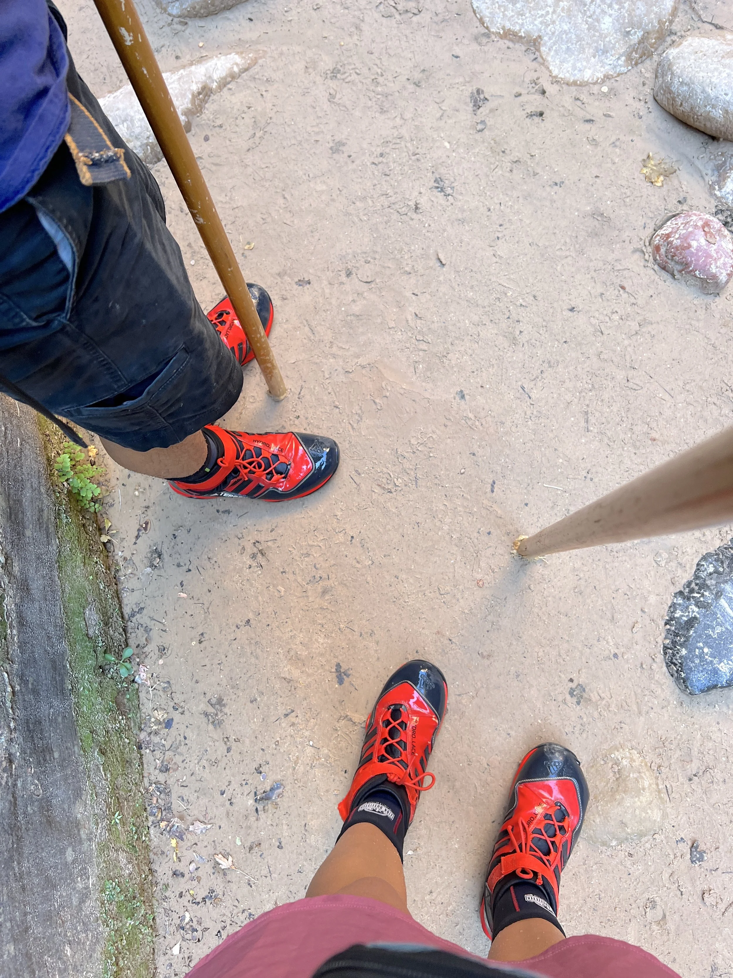 POV shot of rented canyoneering boots, neoprene socks, and a wooden walking stick ready for hiking The Narrows in Zion National Park.
