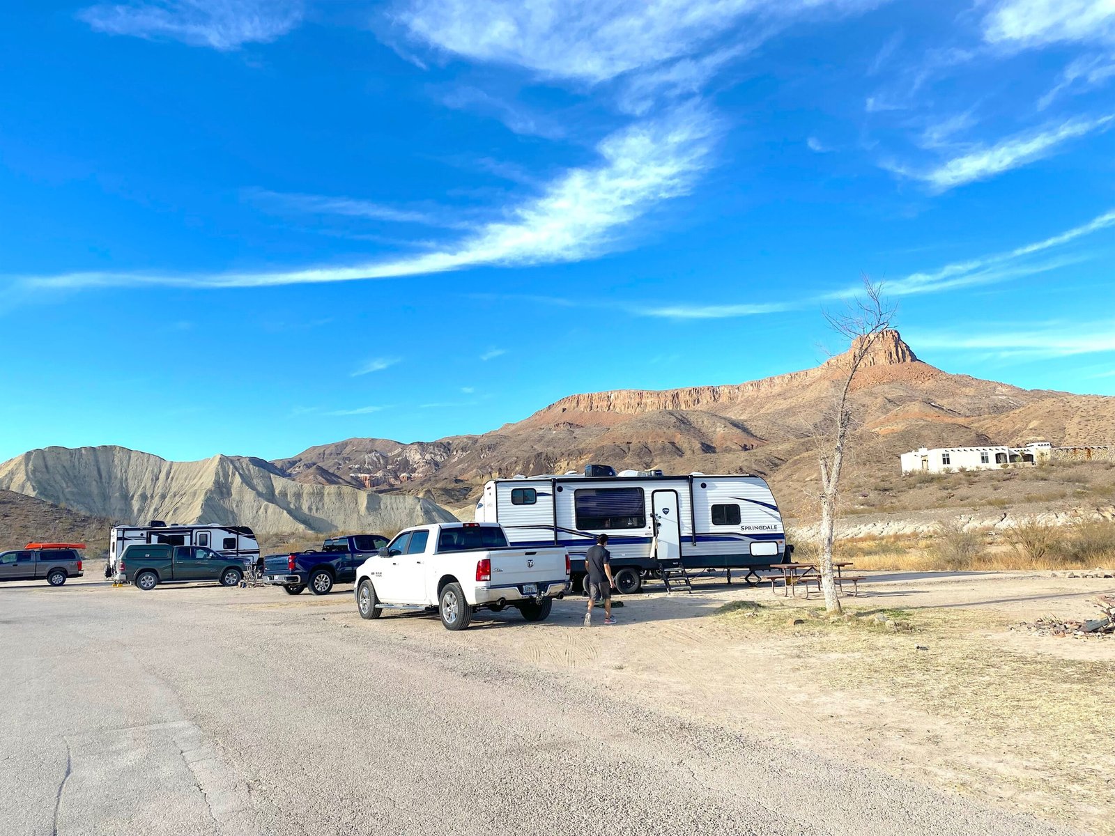 Truck and travel trailer setup at a desert RV campsite with mountains in the background.