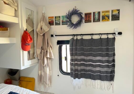 Close-up of a stylish no-sew RV curtain made from a patterned Turkish towel hung with a black rod and Command hooks on a camper wall.
