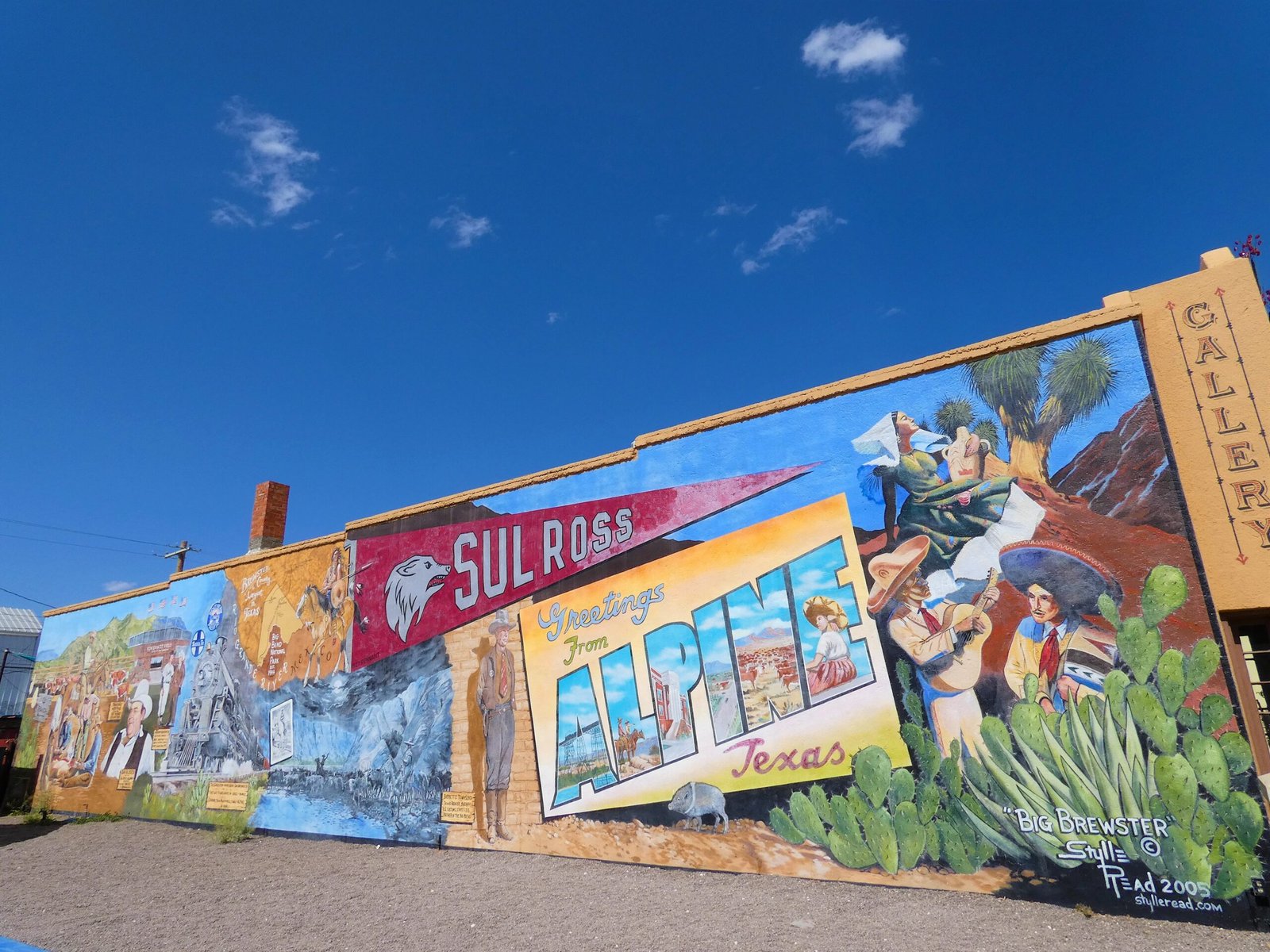 A vibrant, colorful public street mural painted on a building wall in downtown Alpine, Texas.