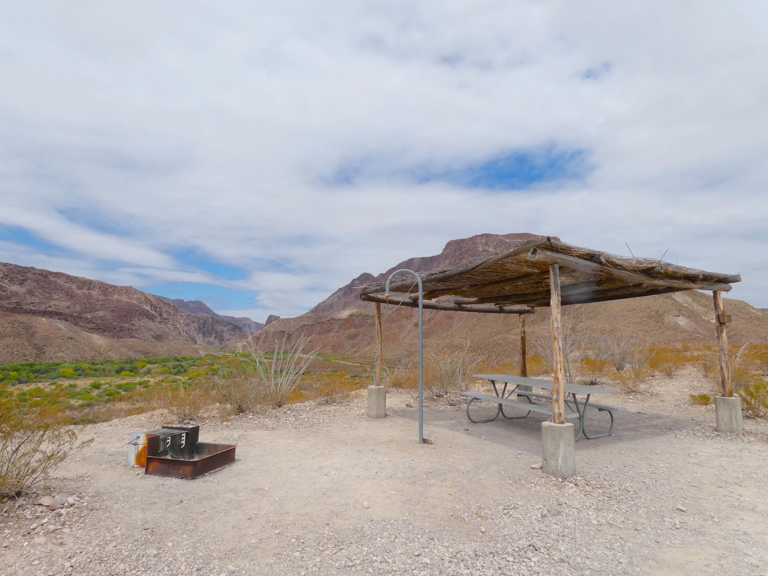 Primitive campsite with shade shelter and desert mountain backdrop in Big Bend Ranch State Park.