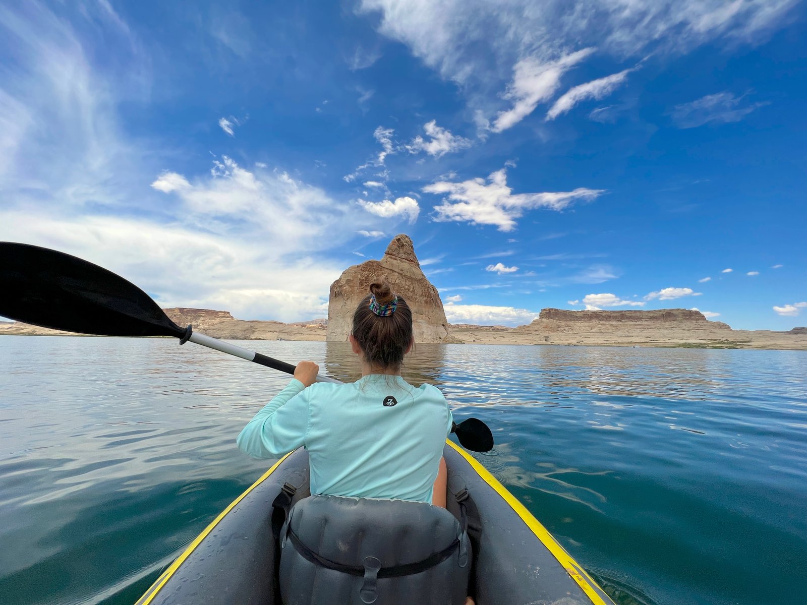 person in inflatable kayak on the river with canyon walls in the distance