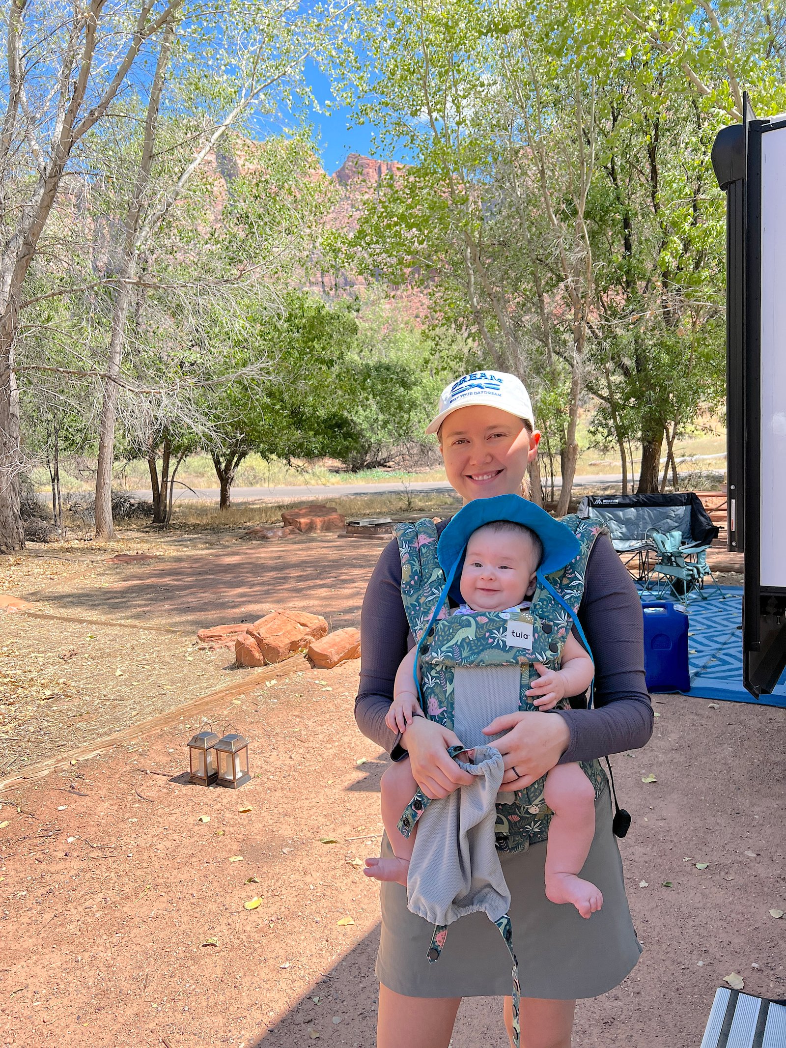 Mother wearing a front-facing baby carrier with her toddler daughter on a trail in Zion National Park.