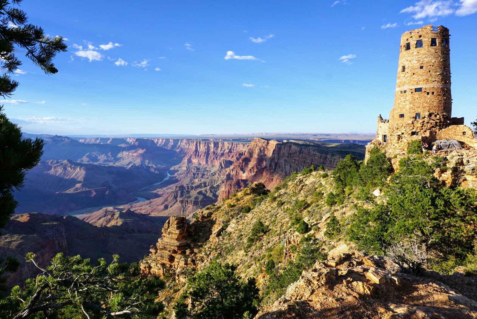 view of desert watchtower on the right and the Grand Canyon with the Colorado River running through on the left