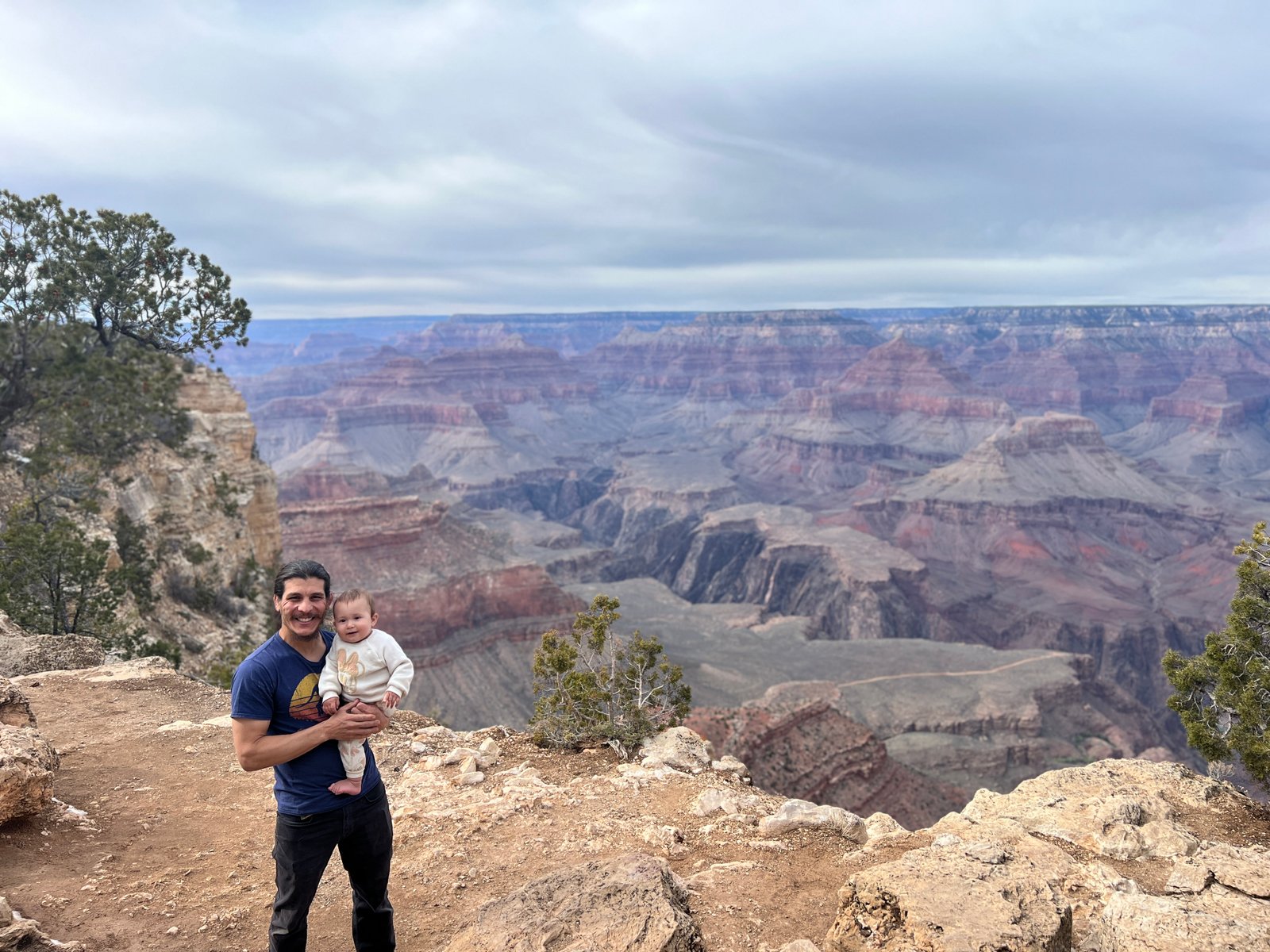 man holding baby near edge of Grand Canyon