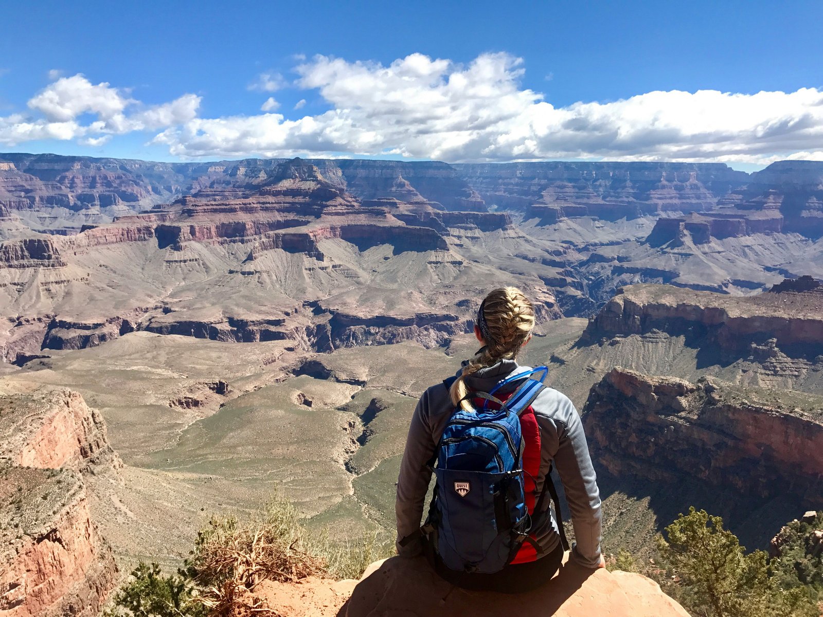 person sitting on cliff edge with Grand Canyon in the distance
