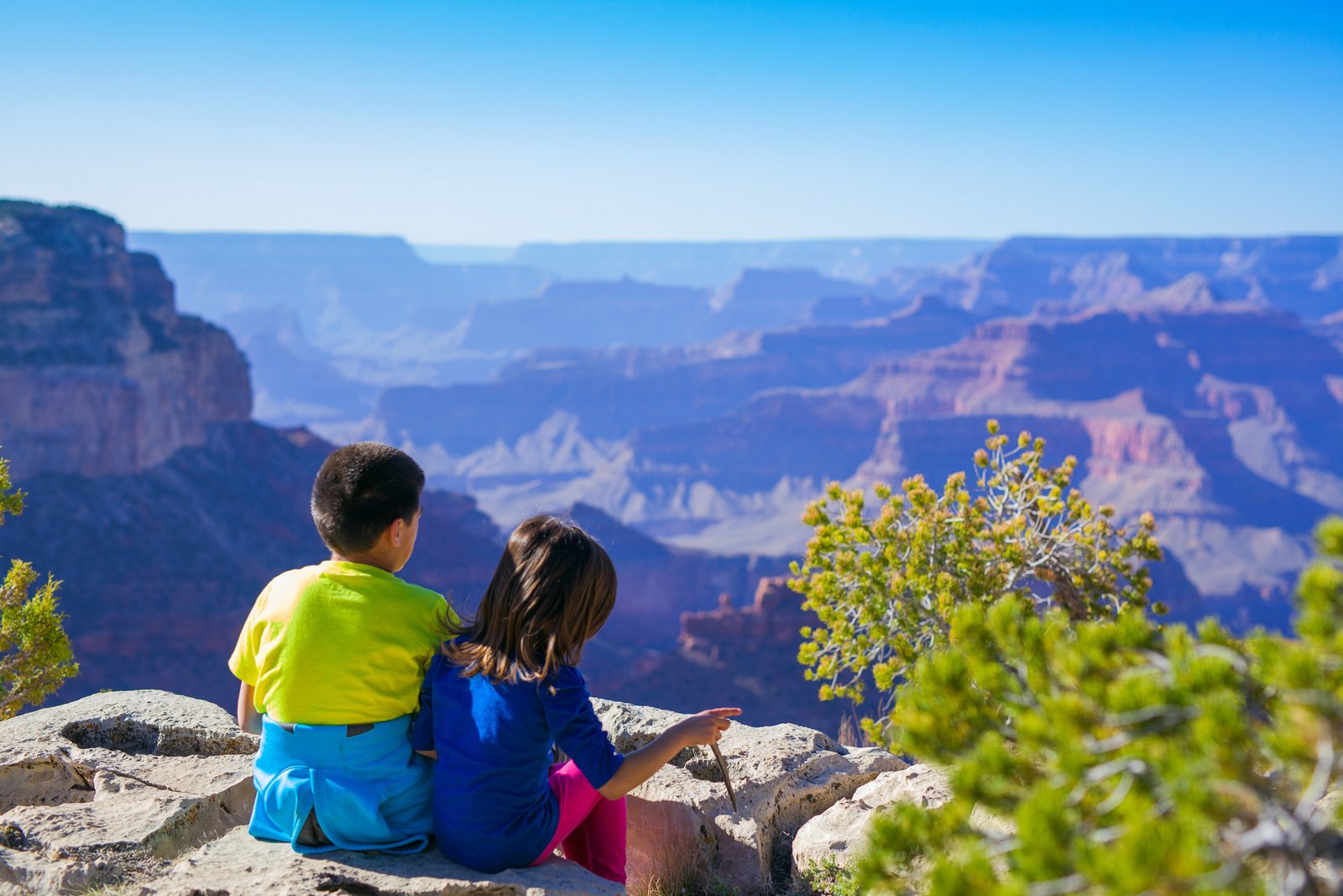 two kids sitting looking out at the Grand Canyon