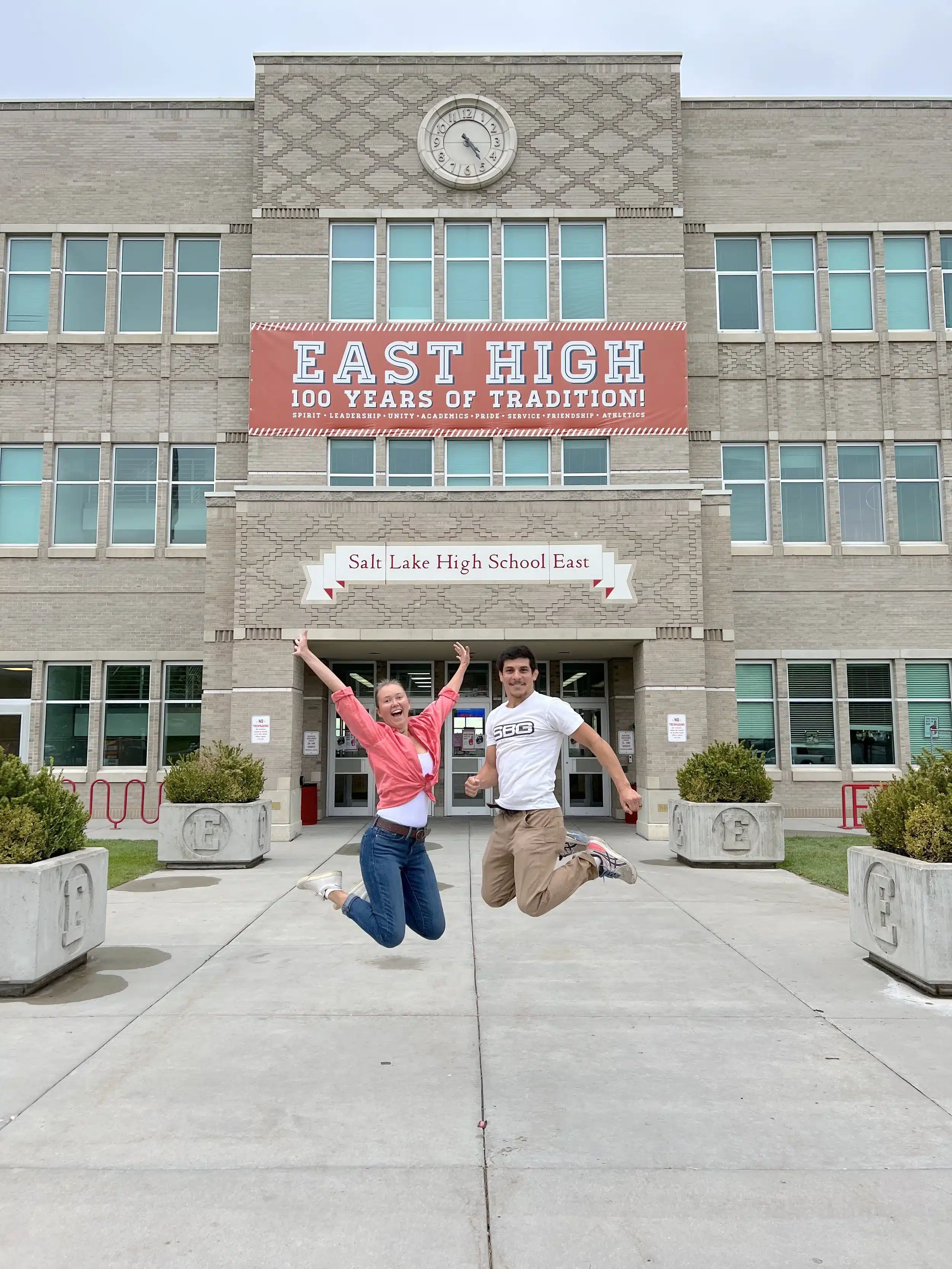 The travel bloggers jumping mid-air in front of the main entrance sign at East High School in Salt Lake City, the real-life High School Musical filming location.