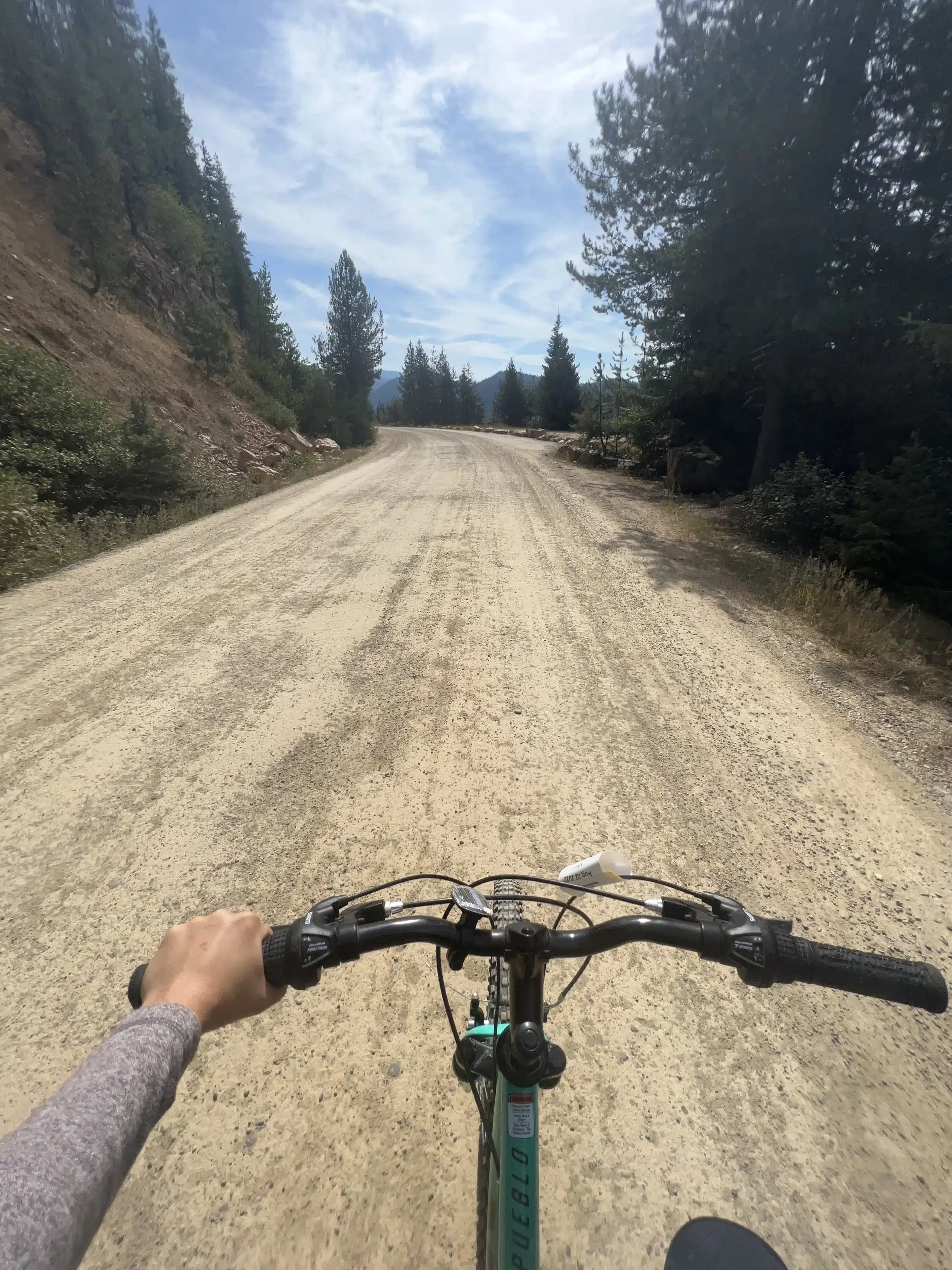 Point-of-view shot looking over bicycle handlebars down at a smooth gravel dirt path on the Route of the Hiawatha.